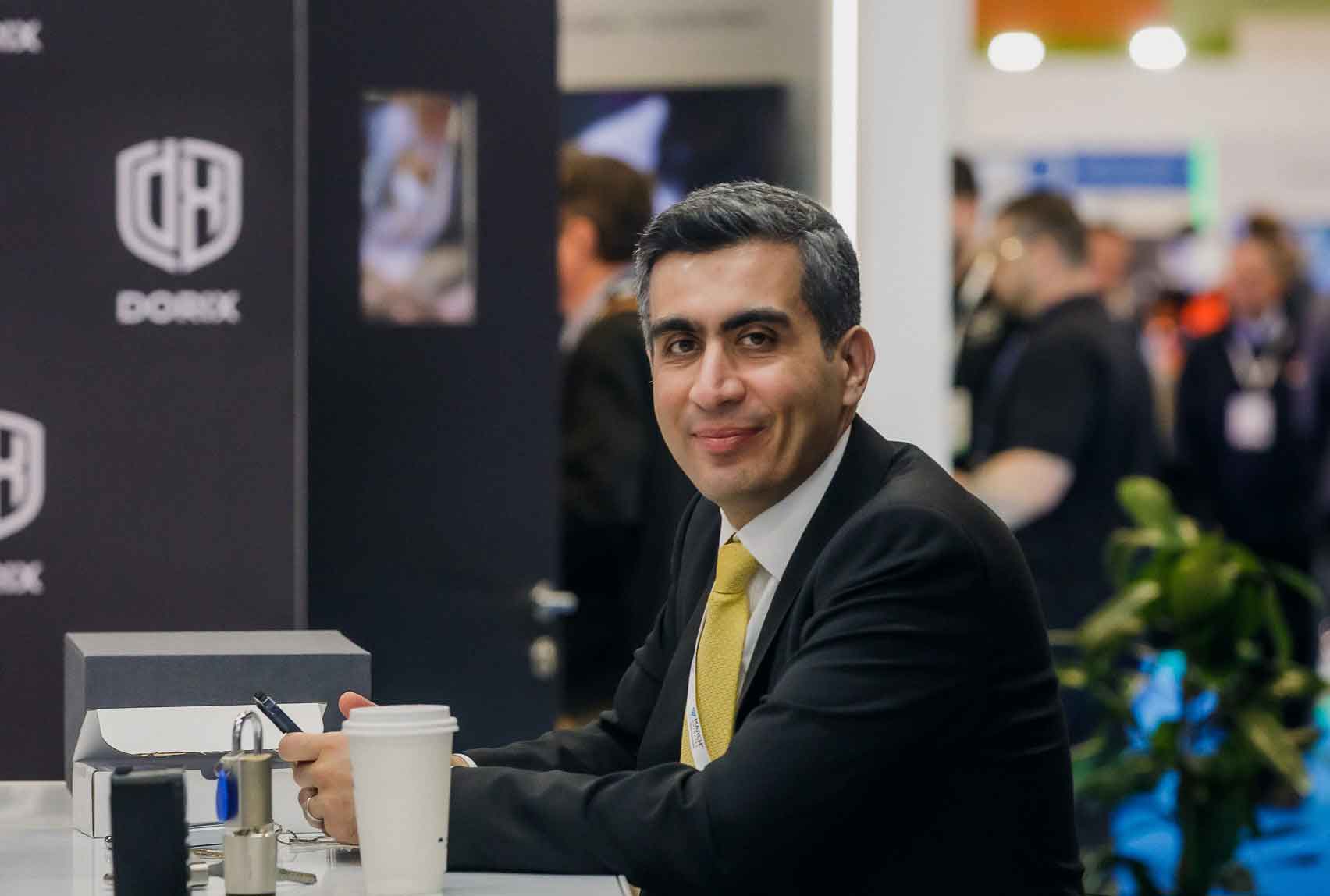 A DORIX executive seated at a trade fair stand, representing innovation in smart door technology and intelligent security systems.
